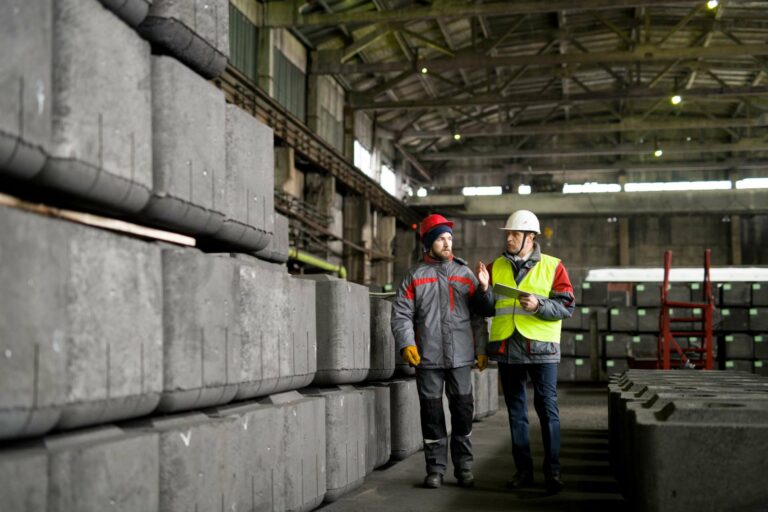 Twee medewerkers in een industriële fabriekshal bespreken productieprocessen